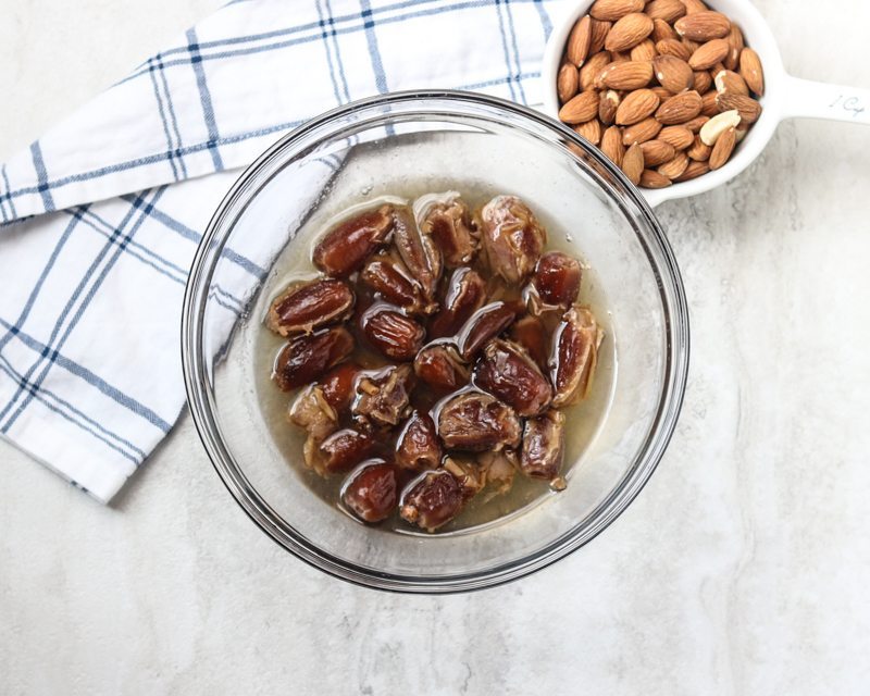 dates soaking in hot water next to almonds