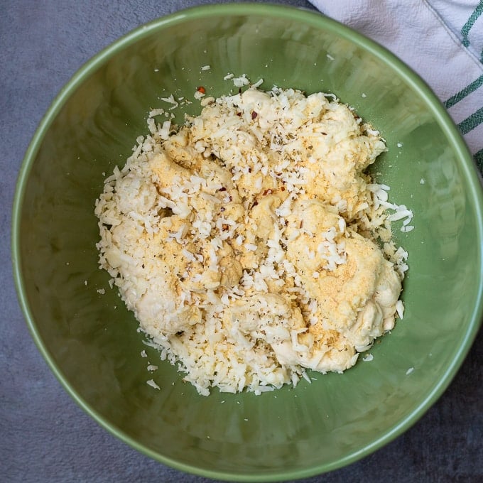 Pizza Dough, cheese, and Italian Seasoning in green mixing bowl.