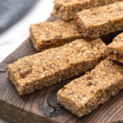 4 Chewy Gluten Free Granola Bars on parchment paper with oats and dates to the side