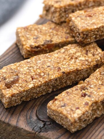 4 Chewy Gluten Free Granola Bars on parchment paper with oats and dates to the side