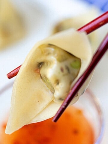 Close up of vegetable potsticker on chopsticks.