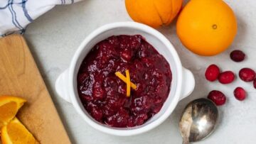 Cranberry Sauce with orange slices on wooden cutting board.