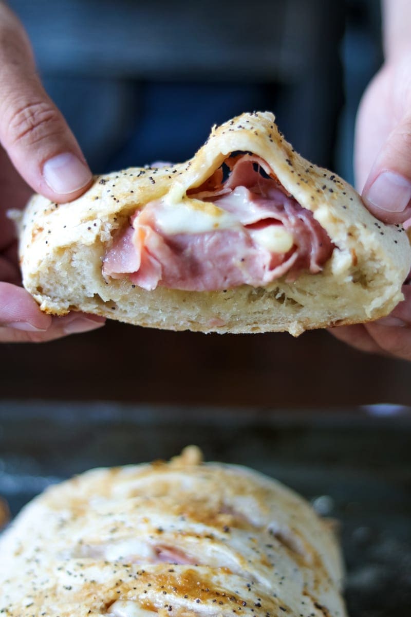 Slice of Ham and Cheese Stromboli being held by two hands.