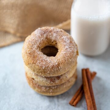 Baked Cinnamon Sugar Donuts Stacked up next to glass of milk