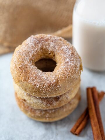 Baked Cinnamon Sugar Donuts Stacked up next to glass of milk