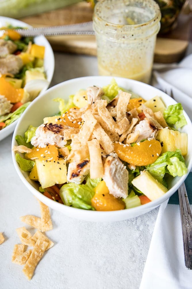 Bowl of Caribbean Chicken Salad with orange dressing in the background. 