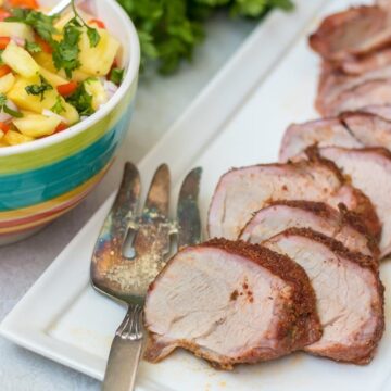 Grilled Pork Tenderloin on white platter next to pineapple salsa