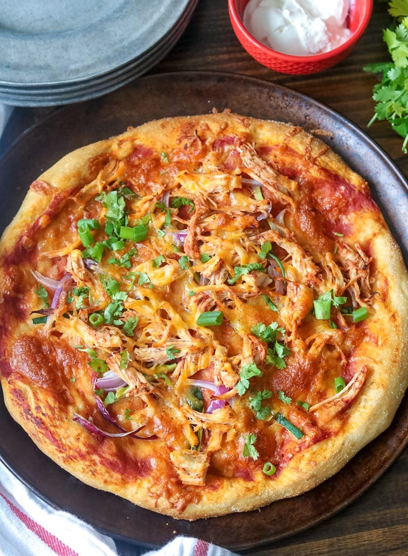 Chicken Fajita pizza on a rustic pizza pan and silver dishes to the side. 