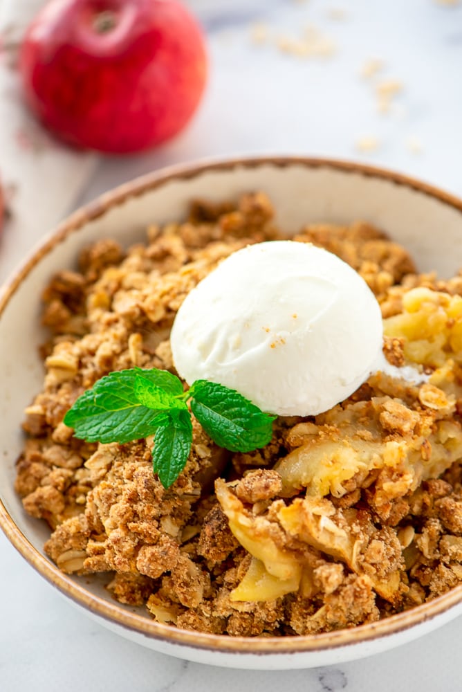 Spoonful of Homemade Apple Crisp Recipe coming out of white baking dish.