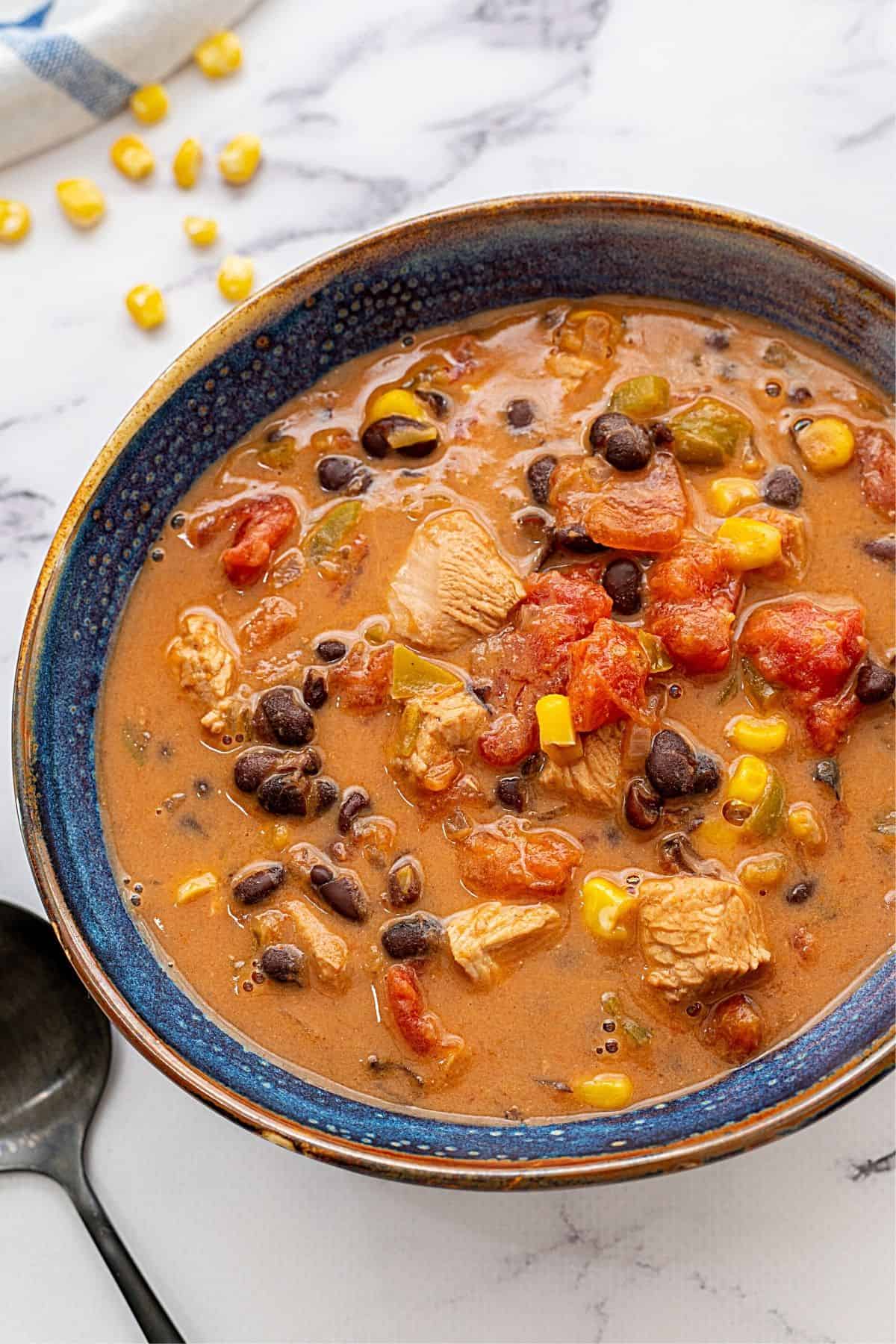 Bowl filled with a creamy soup with chunks of leftover chicken or turkey, corn, and black beans.