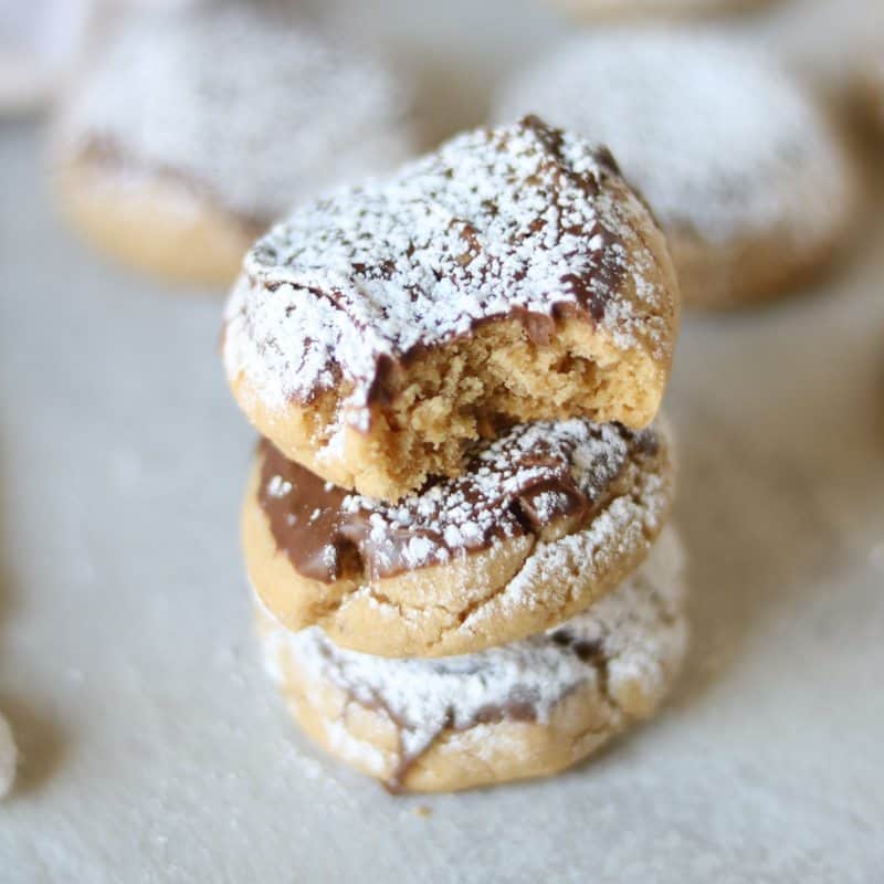 Peanut Butter Chocolate Cookies AKA Muddy Buddy Cookies: A tender peanut butter cookie is dipped in milk chocolate and then dusted with powdered sugar. 