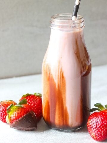 Strawberry Smoothie in glass jar with chocolate covered strawberries on the side of the jar