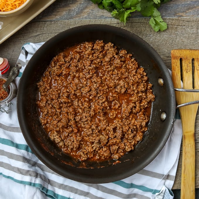 Taco Meat in skillet with wooden spoon.
