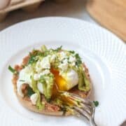 A perfectly poached egg sits upon a spicy refried beans on a toasted muffin and a creamy Avocado Hollandaise. 