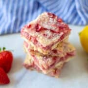 Fresh Strawberry Bars stacked together next to strawberries and lemon