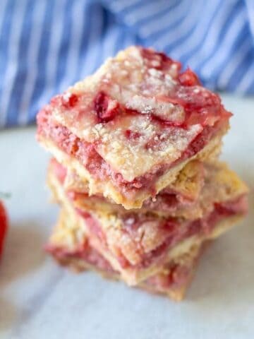 Fresh Strawberry Bars stacked together next to strawberries and lemon