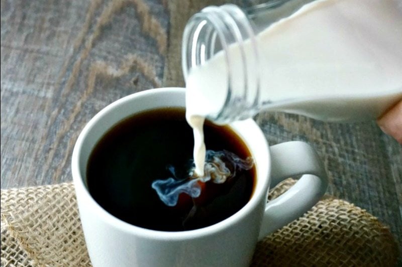 Vanilla Coconut Coffee Creamer being poured into dark coffee