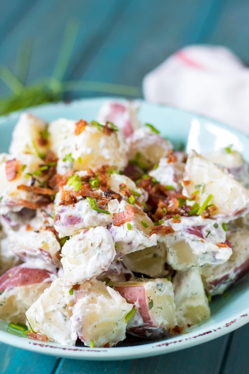 Side view of potato salad with ranch dressing and bacon in blue bowl