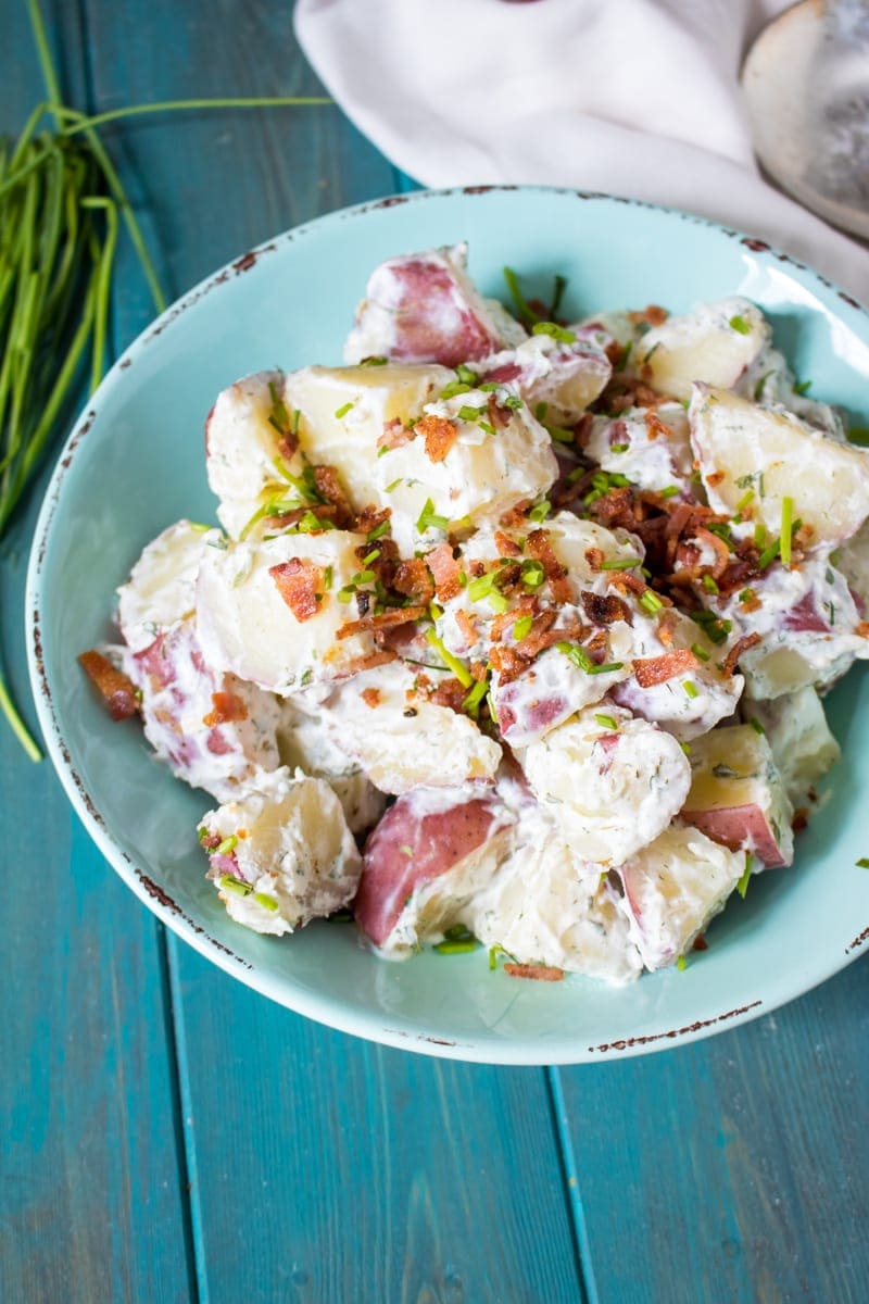 Bacon Ranch Potato Salad in blue bowl with bacon and scallions sprinkled on top