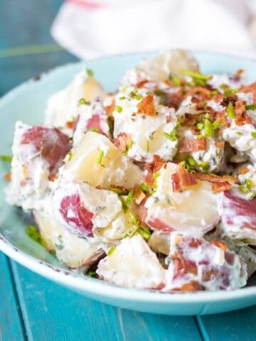 Greek yogurt potato salad in blue bowl with bacon and ranch