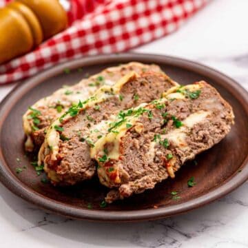 Sliced Meatloaf stuffed with cheese on top of plate.