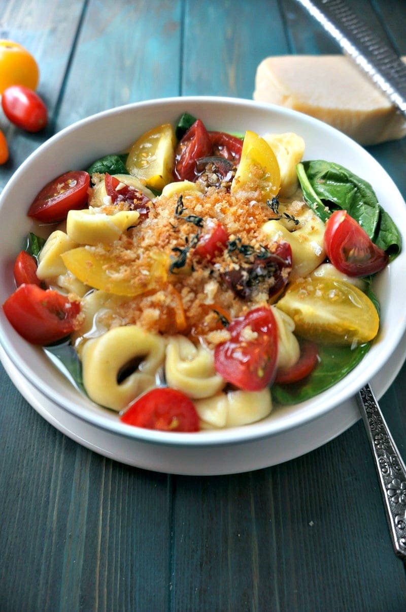 Bowl of Tortellini in Brodo with tomatoes and spinach.