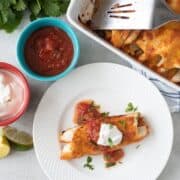 Mexican Breakfast Enchilada on white plate next to salsa and sour cream