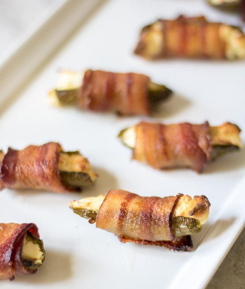 Grilled Jalapeno Poppers wrapped in bacon on white platter