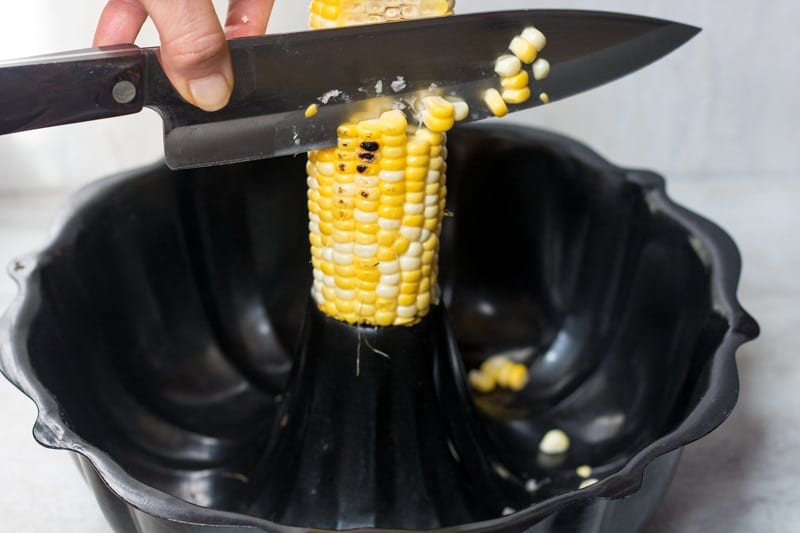 Corn cob resting in bundt pan and kinfe Cutting Corn off the Cob