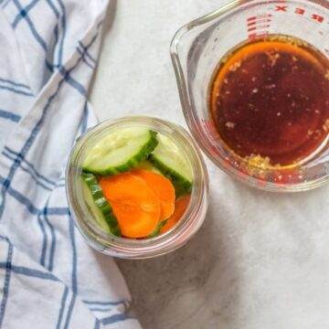 Carrots and baby cucumbers in pint jar with quick pickling liquid to the side