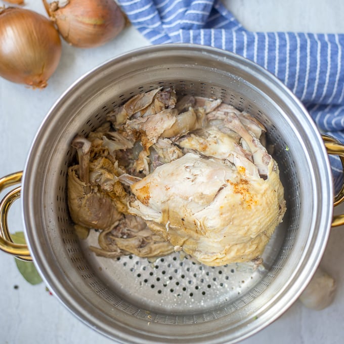 Chicken in strainer over stock pan 