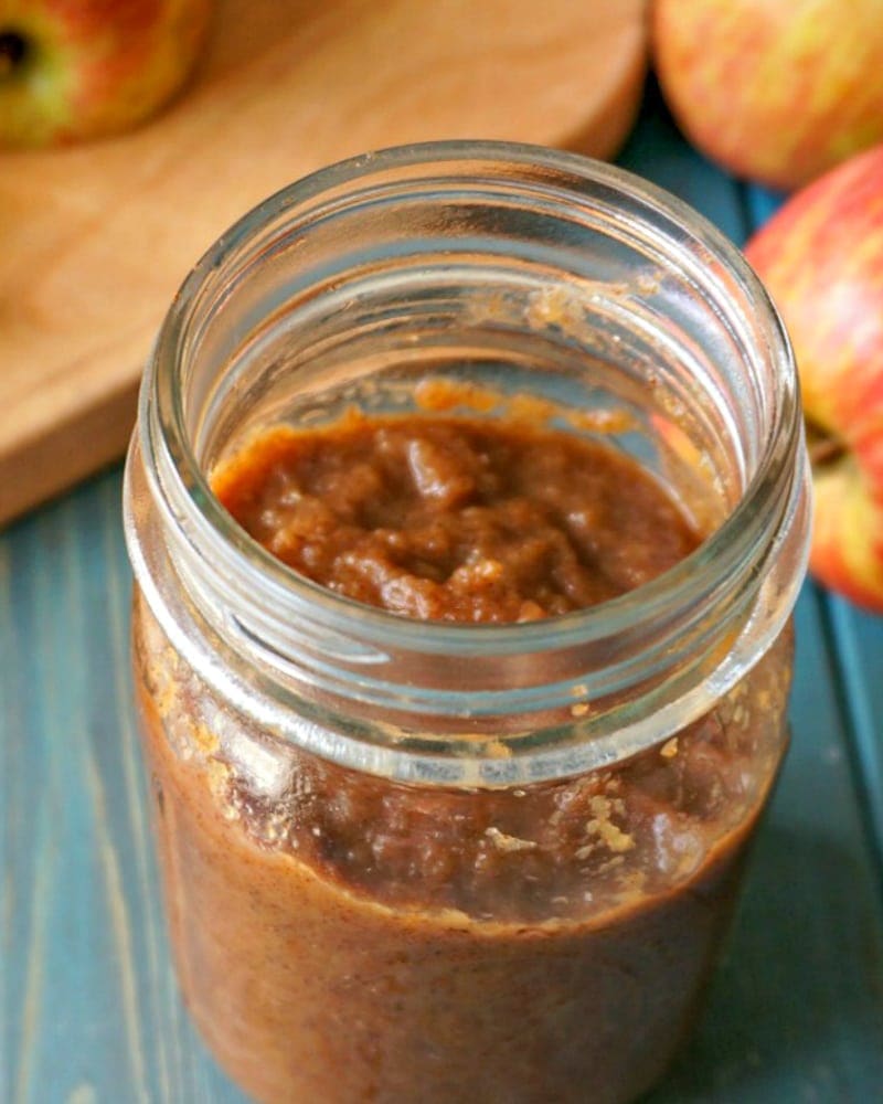 Homemade Apple Butter in glass jar next to fresh apples