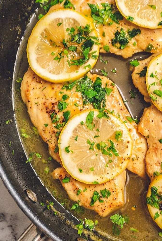 Chicken cutlets in skillet with honey lemon sauce.