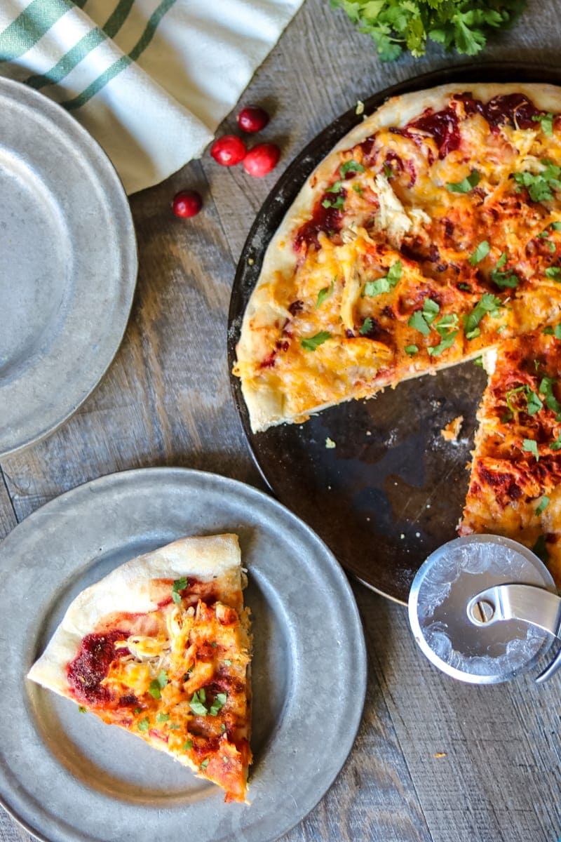 Pizza pan with Cranberry Turkey BBQ Pizza with one slice on a silver plate. 
