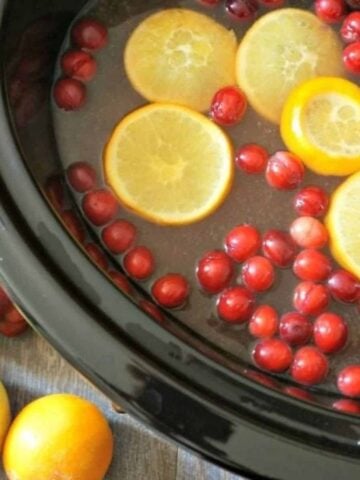 Orange Pineapple Spiced Cider in slow cooker with oranges and cranberries