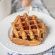 Sweet Potato Waffles on white plate with syrup being poured over waffles