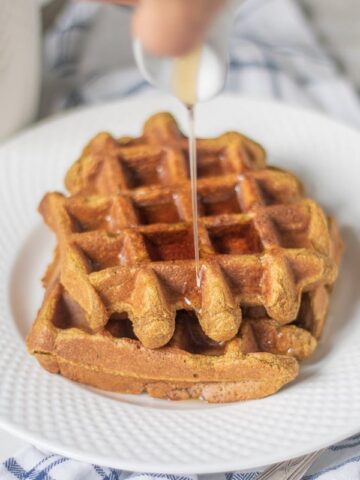 Sweet Potato Waffles on white plate with syrup being poured over waffles