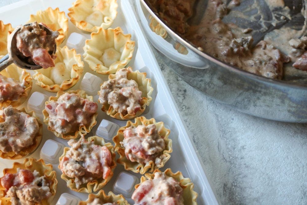 Portioning out creamy taco dip into phyllo cups