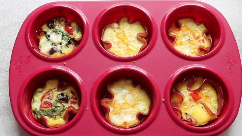 Baked eggs in ham cups in a red silicone muffin tin