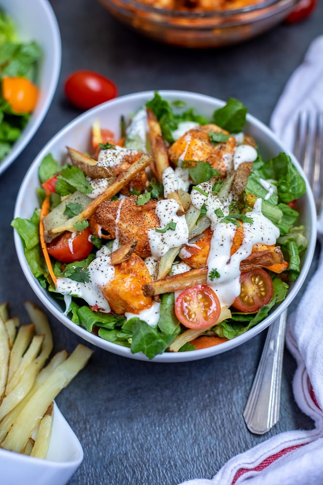 Buffalo Chicken Salad in white bowl next to buffalo chicken and crispy fries