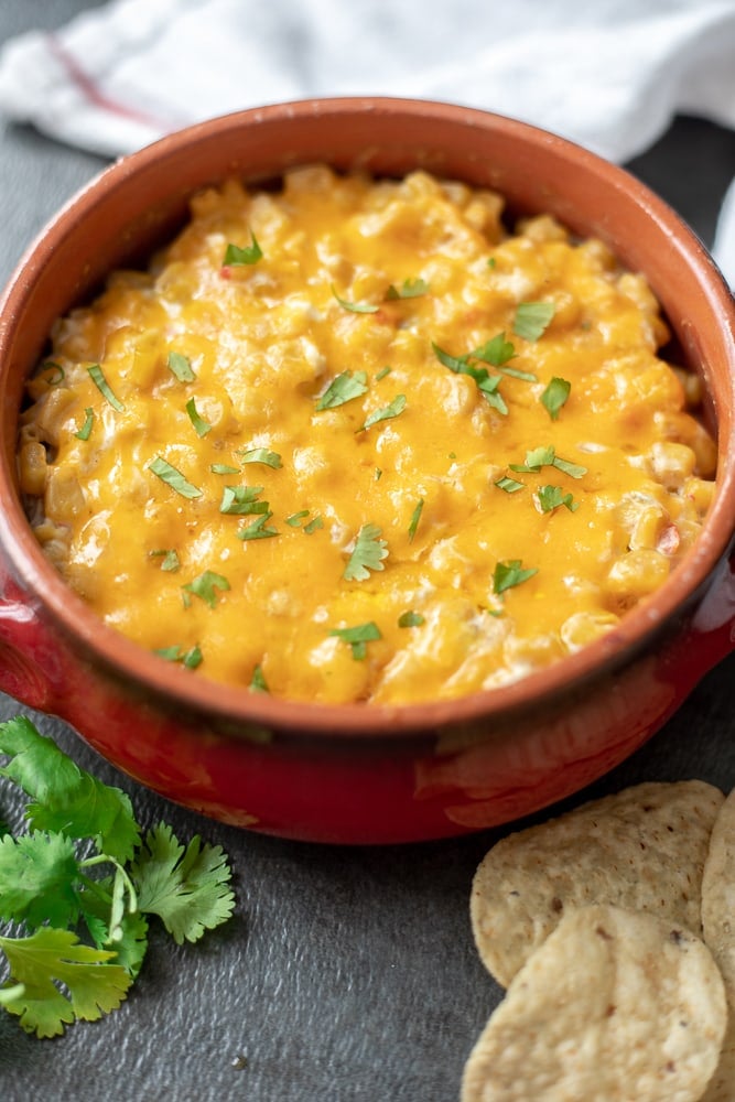 Hot Corn Dip baked in a red crock topped with minced cilantro. 