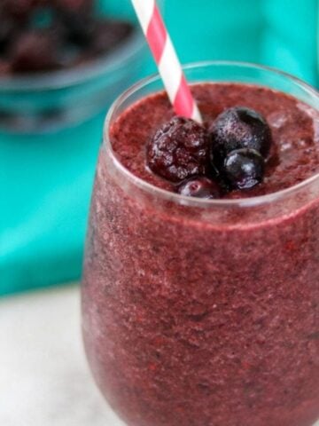 Berry Smoothie in clear glass topped with frozen mixed berries