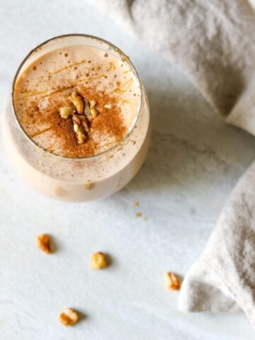 Glass of sweet potato smoothie topped with cinnamon and crushed walnuts