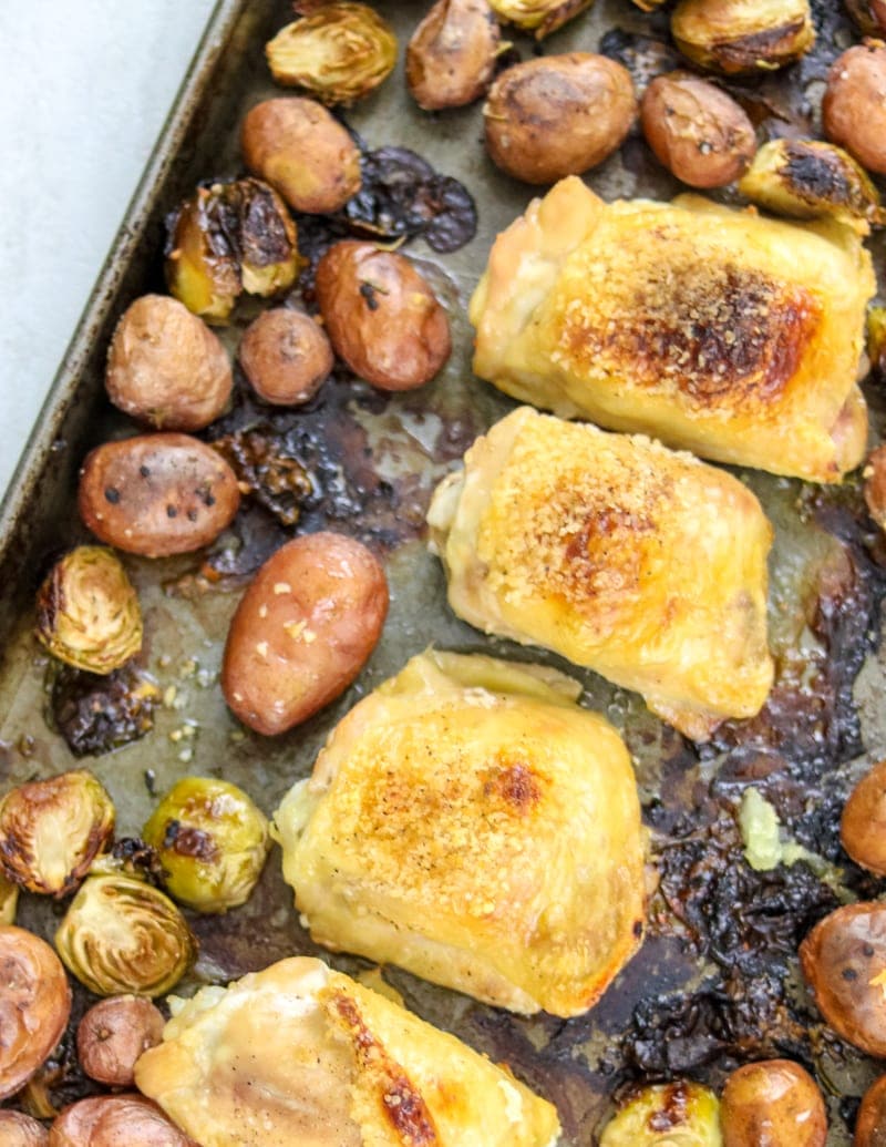Sheet pan with roasted chicken thighs, brussels sprouts, and red potatoes.