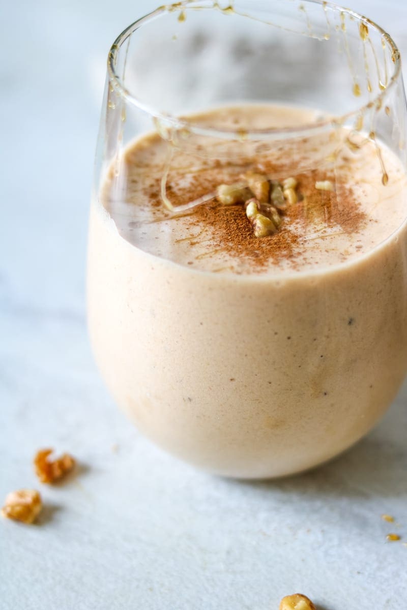 Vegan Sweet Potato Pie Smoothie in clear class with cinnamon, maple and walnuts sprinkled on top. 