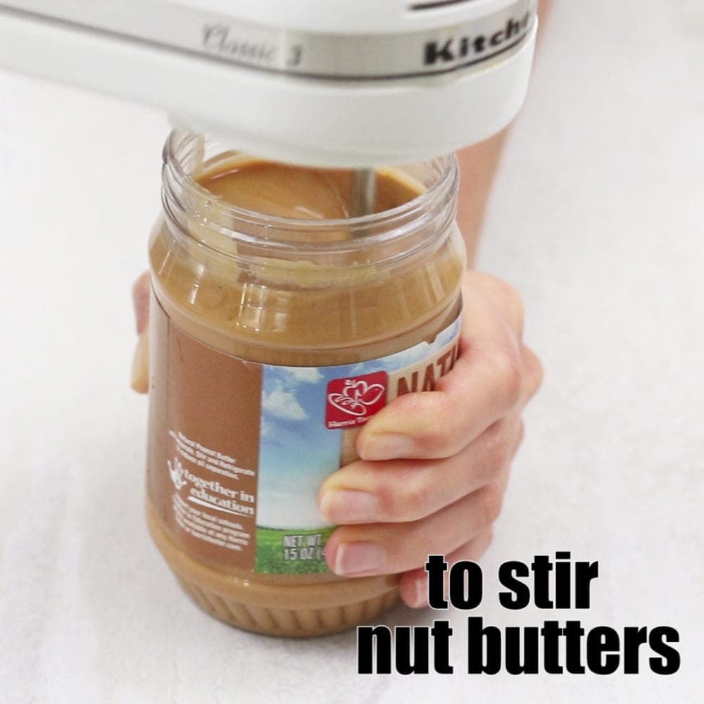 Hand Held Mixer Stirring Peanut Butter with title text that reads to stir nut butters.