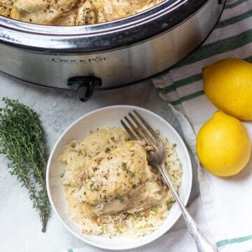 Bowl of lemon garlic rice with chicken thighs next to crock pot