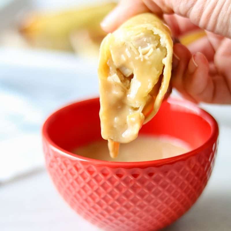 A crispy baked egg roll stuffed with potatoes, turkey, and mashed potatoes dipping into gravy. 