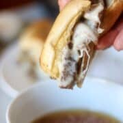 A french dip being dipped into aus jus