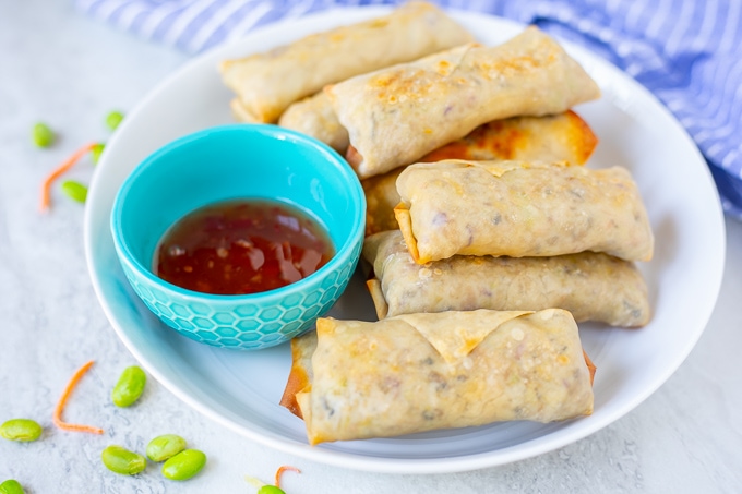 Platter of baked egg rolls next to sweet chili sauce